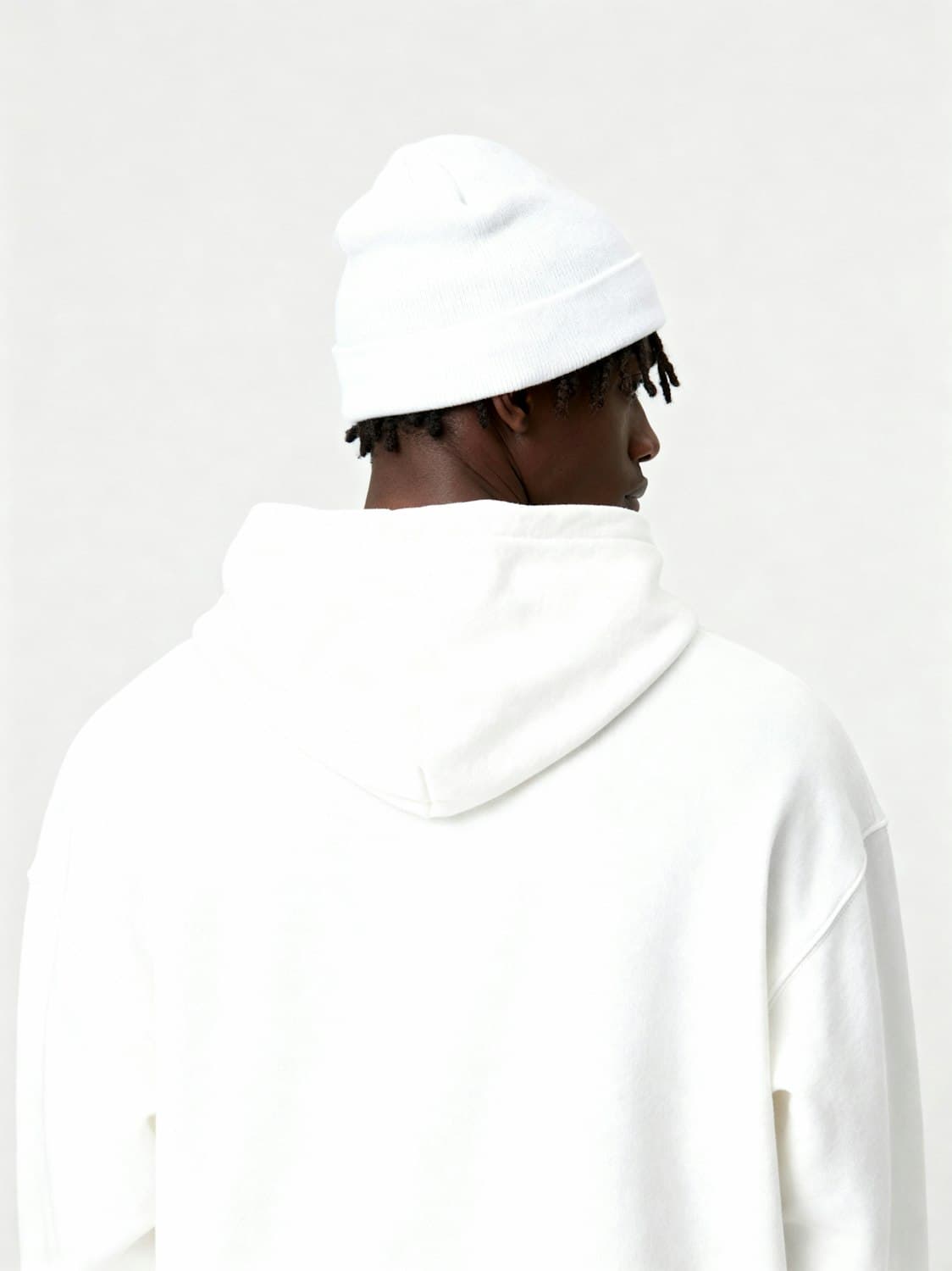 Model in an oversized white hoodie and beanie